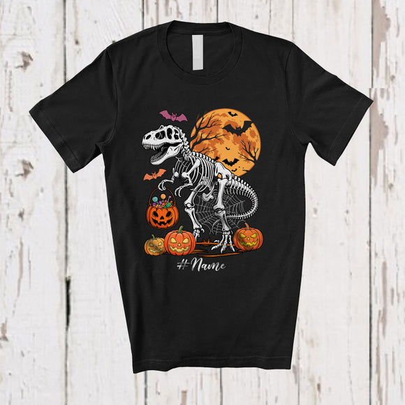 MacnyStore - Personalized Custom Name Skeleton T-Rex Holding Pumpkin Candy; Scary Halloween Moon Dinosaur T-Shirt